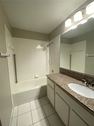 a bathroom with a granite countertop sink a mirror a bathtub and shower