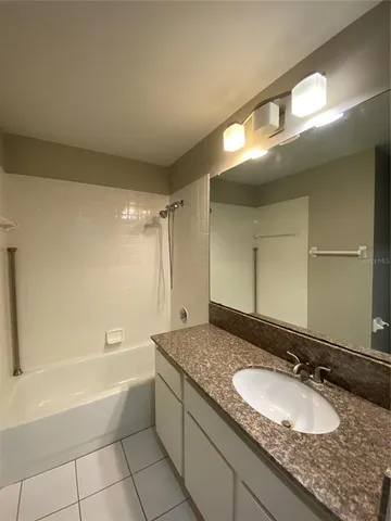 a bathroom with a granite countertop sink mirror and a bathtub