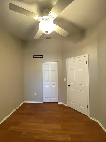 a view of an empty room and chandelier fan