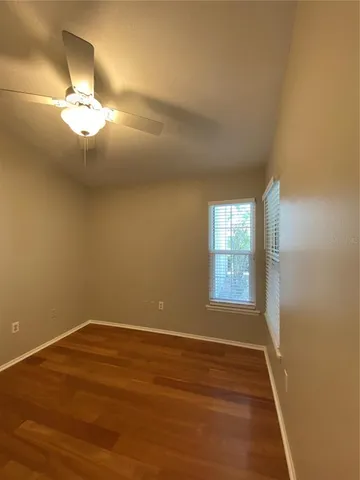 a view of empty room with wooden floor and fan