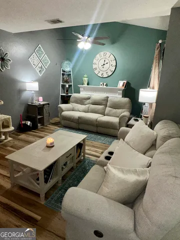 a living room with furniture a clock and a view of kitchen