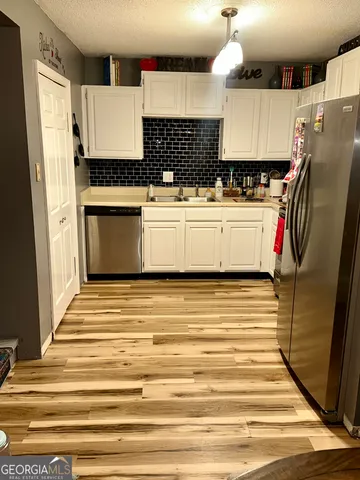 a view of kitchen with stainless steel appliances refrigerator stove and wooden floor