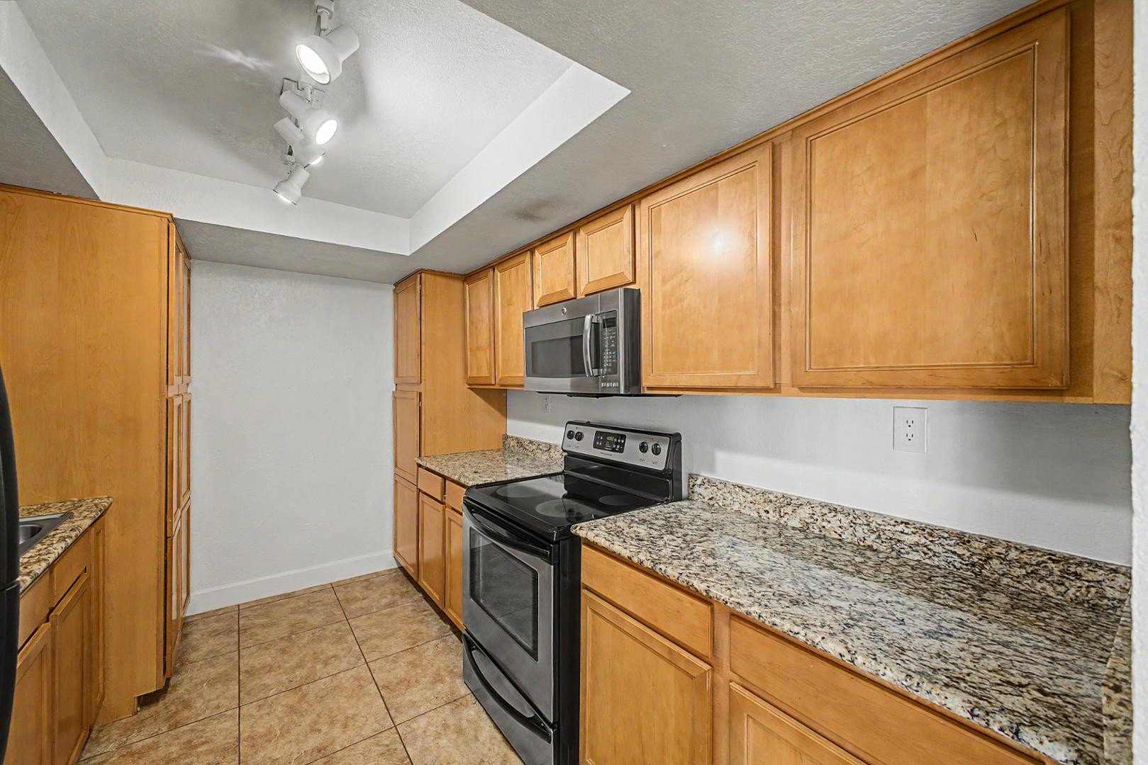 3825 East Camelback Road, Unit 144 Phoenix, AZ 85018 - Photo 8 of 35 a kitchen with stainless steel appliances granite countertop a stove a sink and a microwave