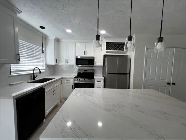 a large kitchen with stainless steel appliances granite countertop a sink a stove a refrigerator and a kitchen island