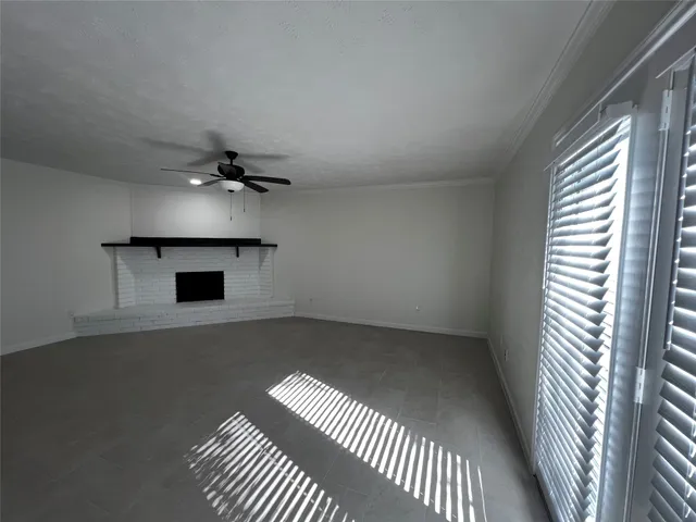 an empty room with a fireplace and chandelier fan