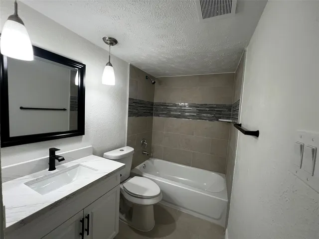 a bathroom with a granite countertop sink toilet a mirror and bathtub