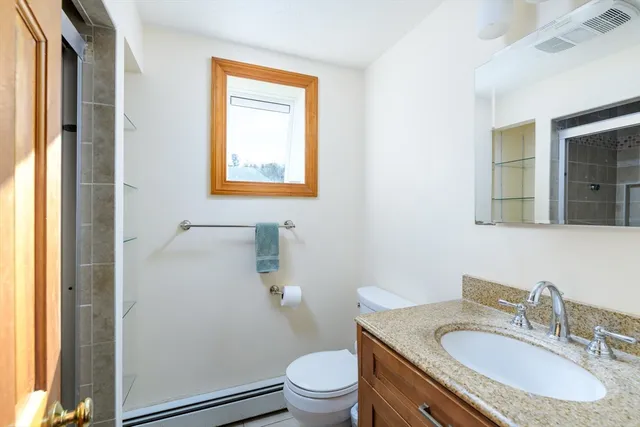 a bathroom with a granite countertop toilet a sink and a mirror