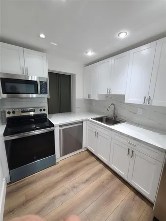 a kitchen with granite countertop white cabinets and stainless steel appliances