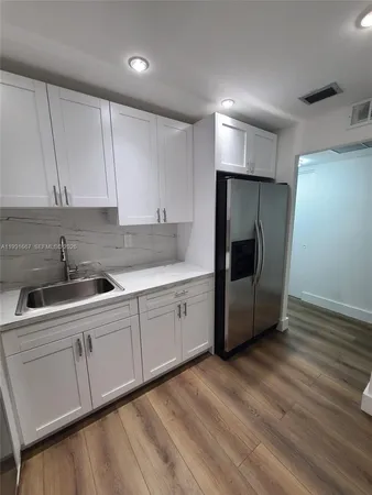 a kitchen with a sink a refrigerator and cabinets