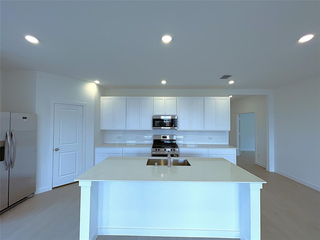 3020 Dutch Road Providence Village, TX 76227 - Photo 6 of 23 a kitchen with kitchen island a stove a sink and a refrigerator