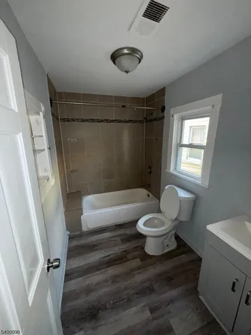 a bathroom with a granite countertop bathtub shower sink vanity and toilet