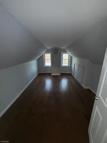a view of an empty room with wooden floor and windows