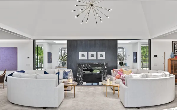 a living room with couches a fireplace and dining table with wooden floor