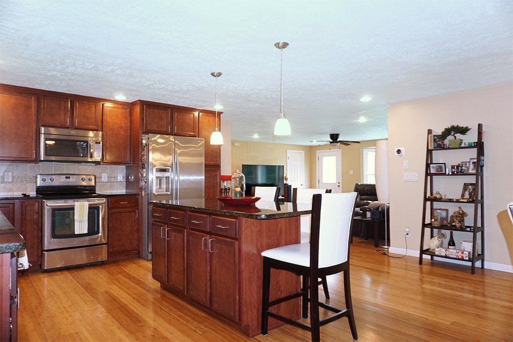 92 Ellendale Circle Springfield, MA 01128 - Photo 3 of 25 a kitchen with stainless steel appliances granite countertop a stove top oven a sink a dining table and chairs with wooden floor