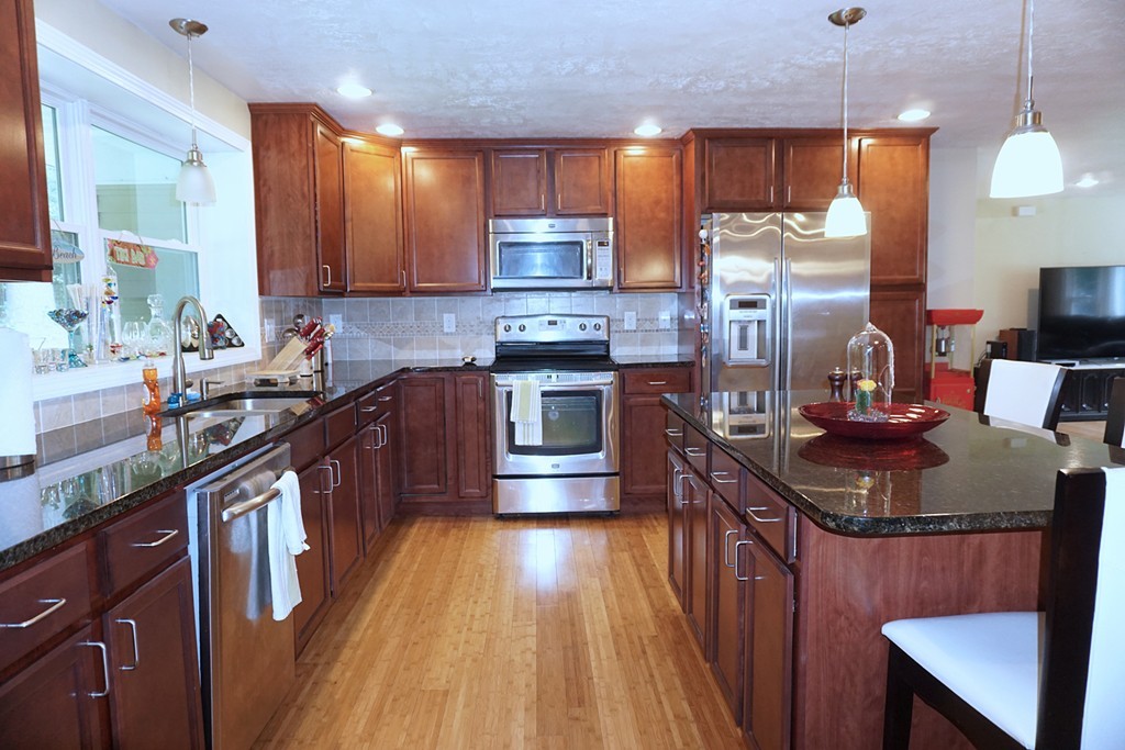 92 Ellendale Circle Springfield, MA 01128 - Photo 10 of 25 a kitchen with stainless steel appliances granite countertop a stove a sink dishwasher a microwave oven and a dining table with wooden cabinet