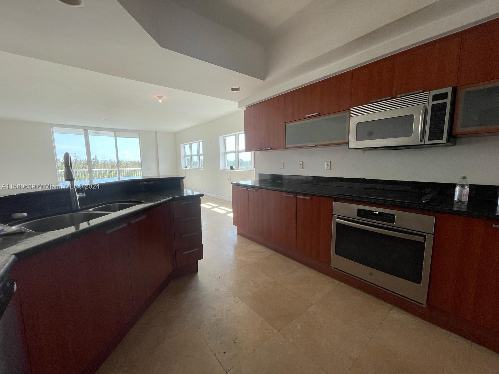 a large kitchen with stainless steel appliances wooden cabinets and a stove top oven
