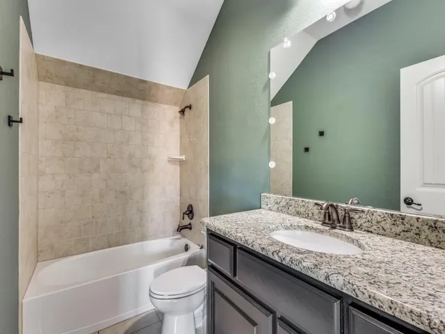 a bathroom with a granite countertop sink a toilet and shower