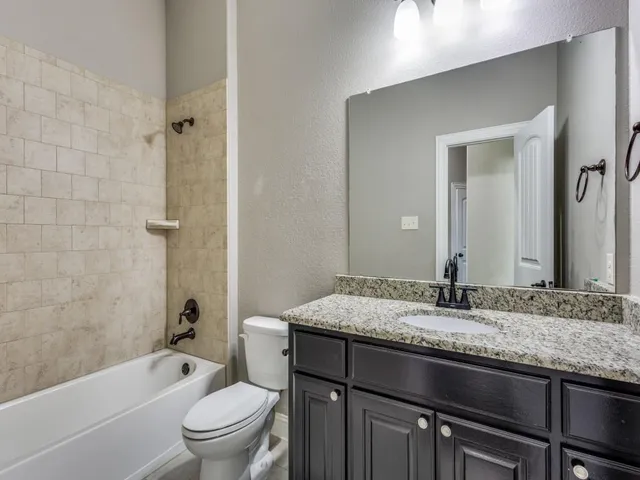 a bathroom with a granite countertop sink a toilet and bathtub