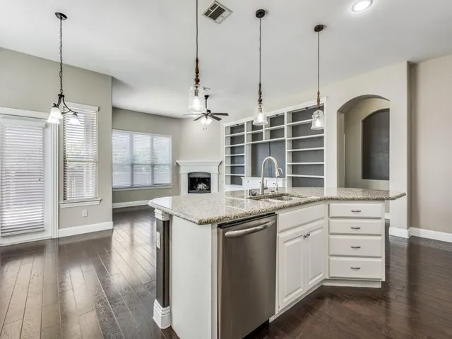 a kitchen with stainless steel appliances kitchen island granite countertop a stove a sink and white cabinets with wooden floor