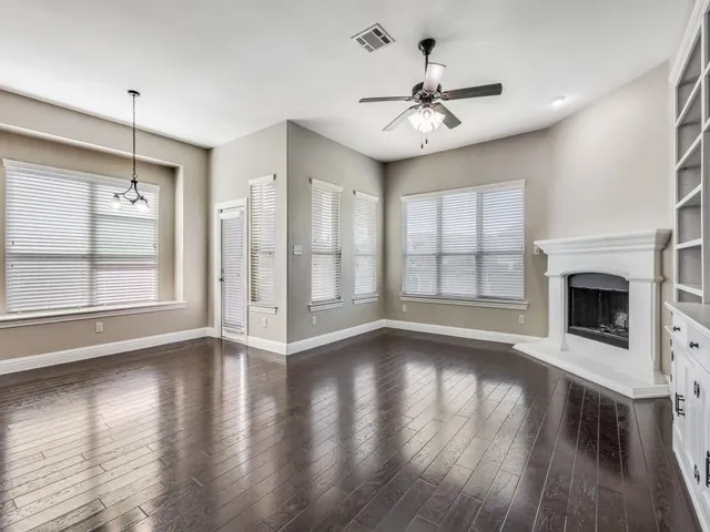 a view of an empty room with wooden floor fireplace and a window