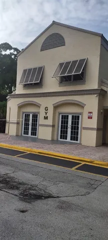 a view of white house with a yard and potted plants