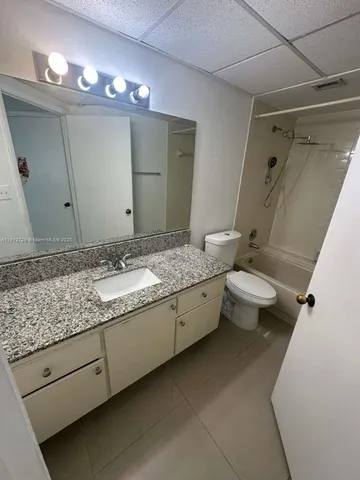 a bathroom with a granite countertop sink a toilet and a mirror