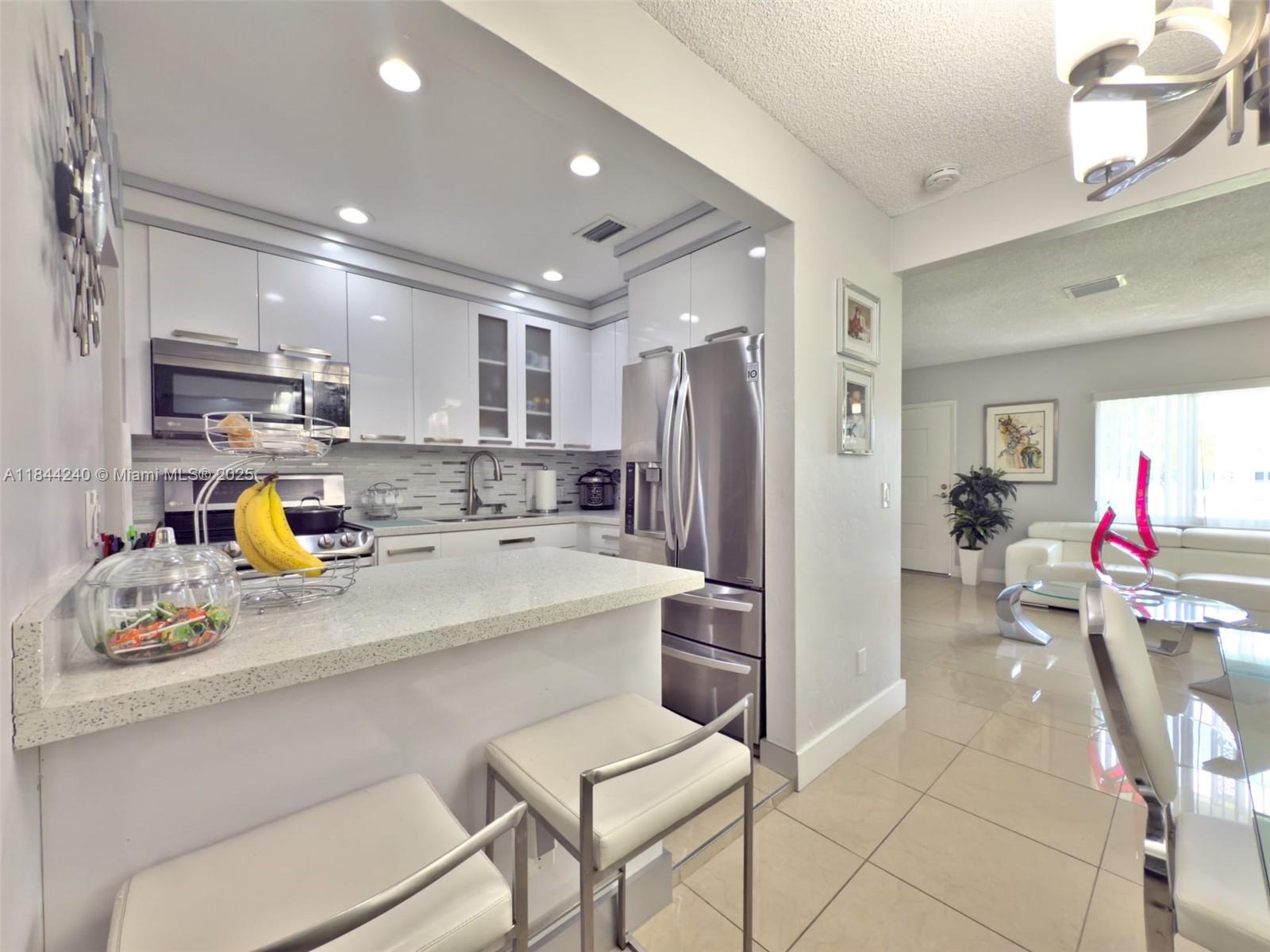 6290 Southwest 37th Street Miami, FL 33155 - Photo 26 of 34 a kitchen with stainless steel appliances granite countertop a refrigerator and a stove top oven