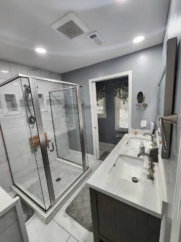a bathroom with a sink a mirror and a glass door shower