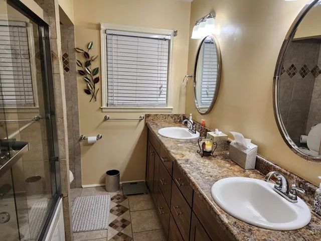 a bathroom with a granite countertop double vanity sink and a mirror