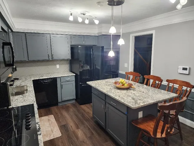 a kitchen with stainless steel appliances granite countertop wooden cabinets a sink dishwasher a stove and a refrigerator with wooden floor