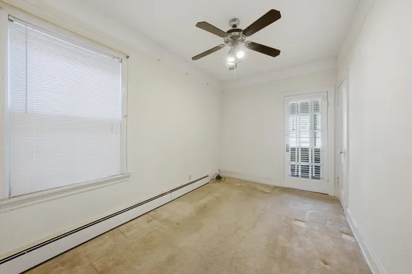 an empty room with chandelier fan and windows