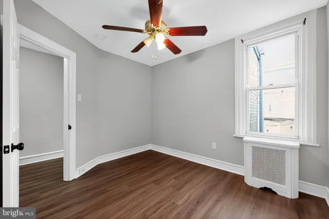 an empty room with wooden floor closet and windows
