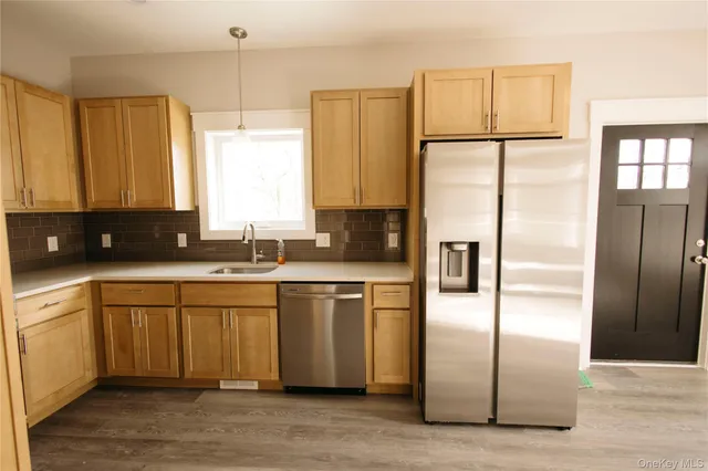 a kitchen with stainless steel appliances granite countertop a refrigerator a sink a stove and white cabinets with wooden floor