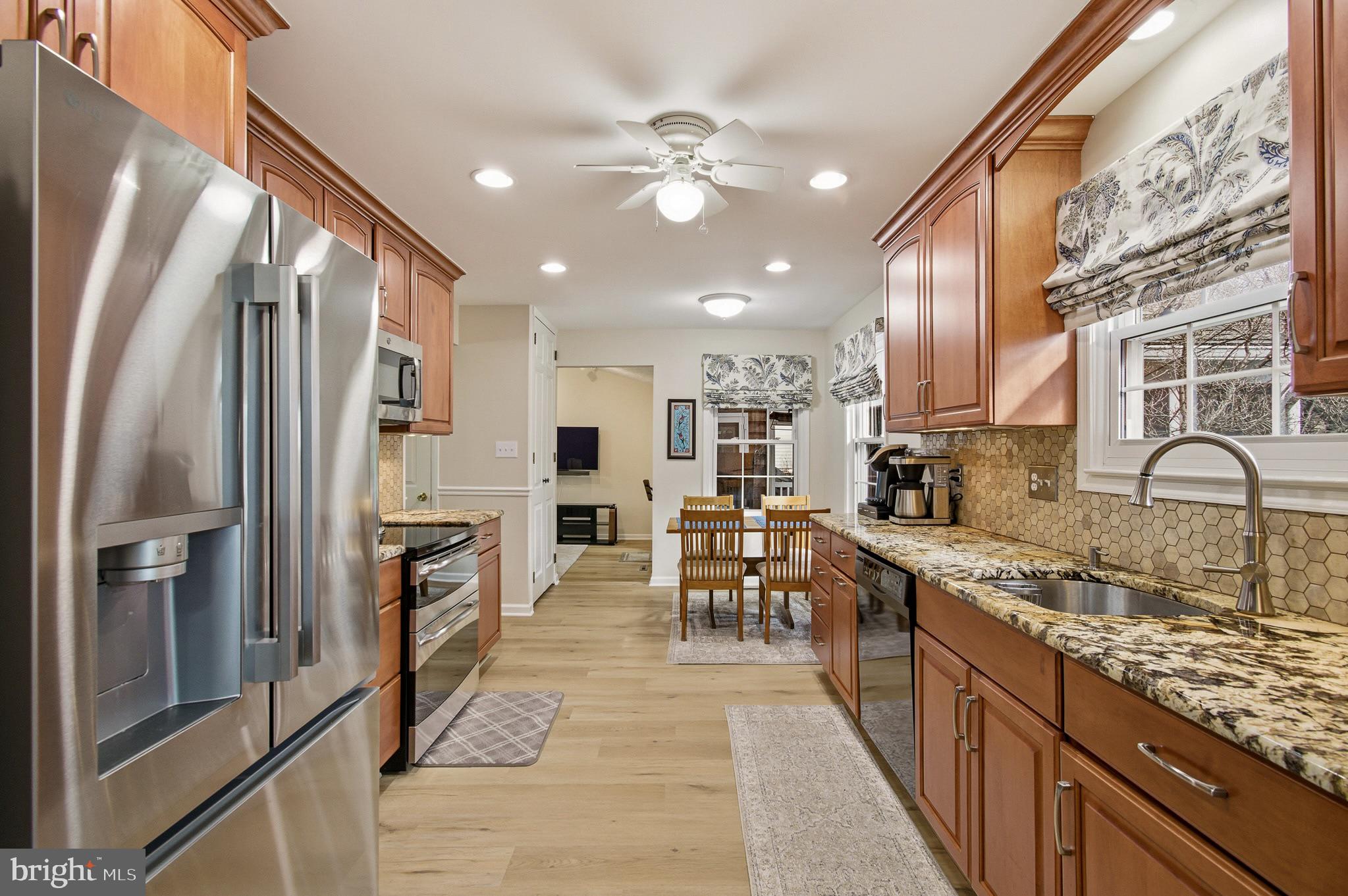 4705 Ilkley Moor Lane Ellicott City, MD 21043 - Photo 12 of 69 a kitchen with stainless steel appliances granite countertop a refrigerator a sink a stove and white cabinets with wooden floor