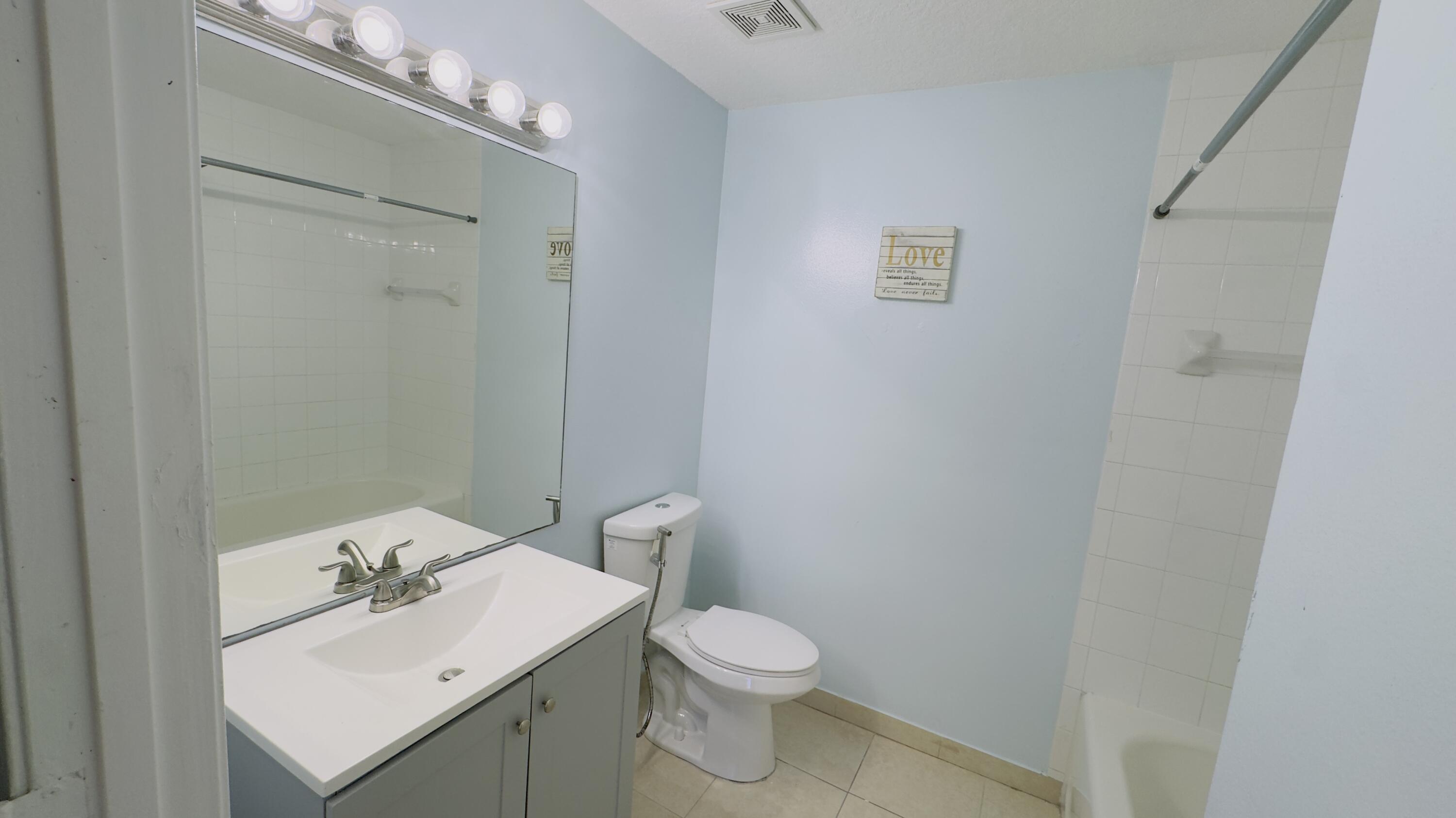 3481 Briar Bay Boulevard, Unit 201 West Palm Beach, FL 33411 - Photo 15 of 19 a bathroom with a sink a toilet and mirror