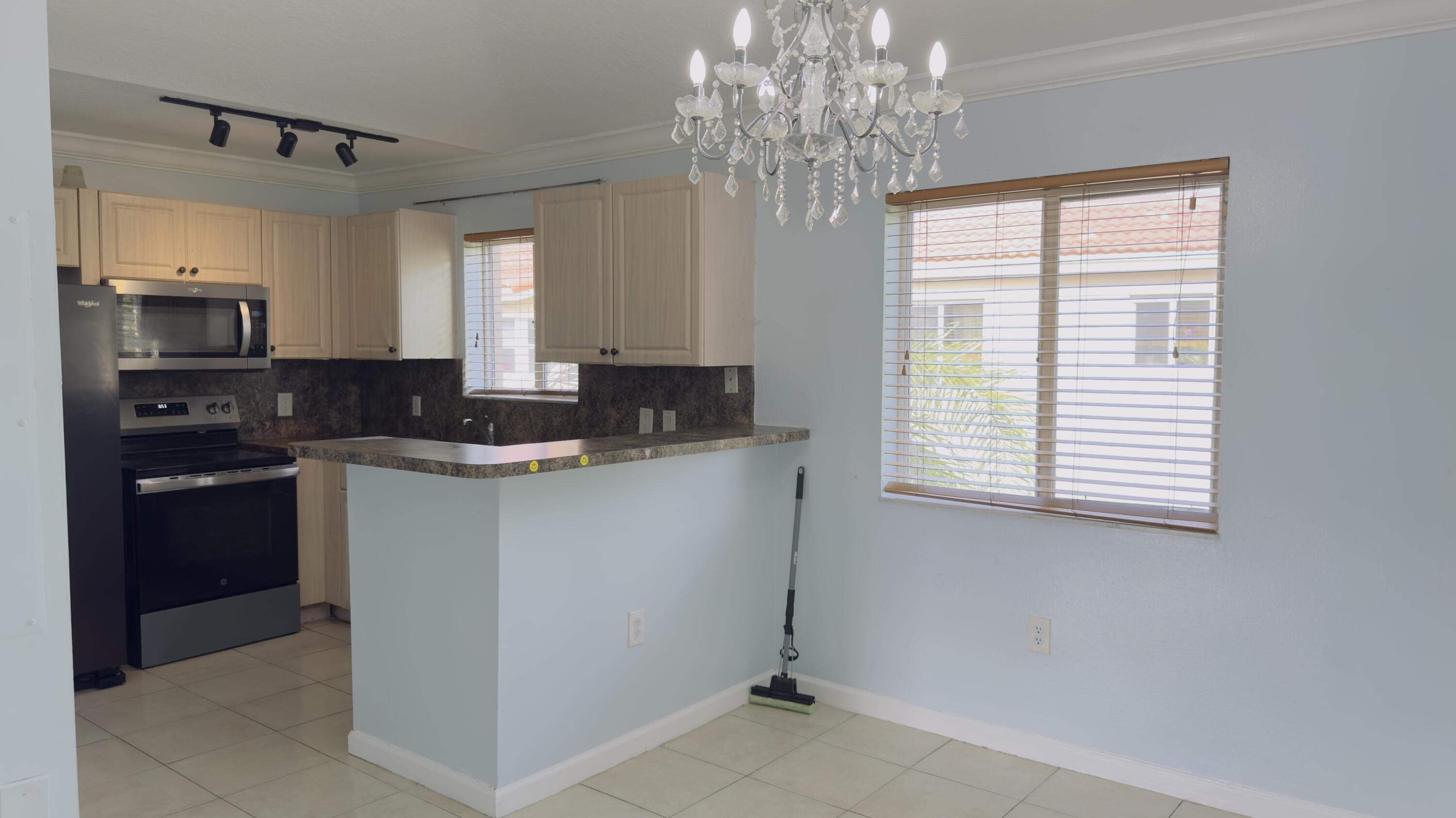 3481 Briar Bay Boulevard, Unit 201 West Palm Beach, FL 33411 - Photo 7 of 19 a kitchen with granite countertop a sink stainless steel appliances and a window
