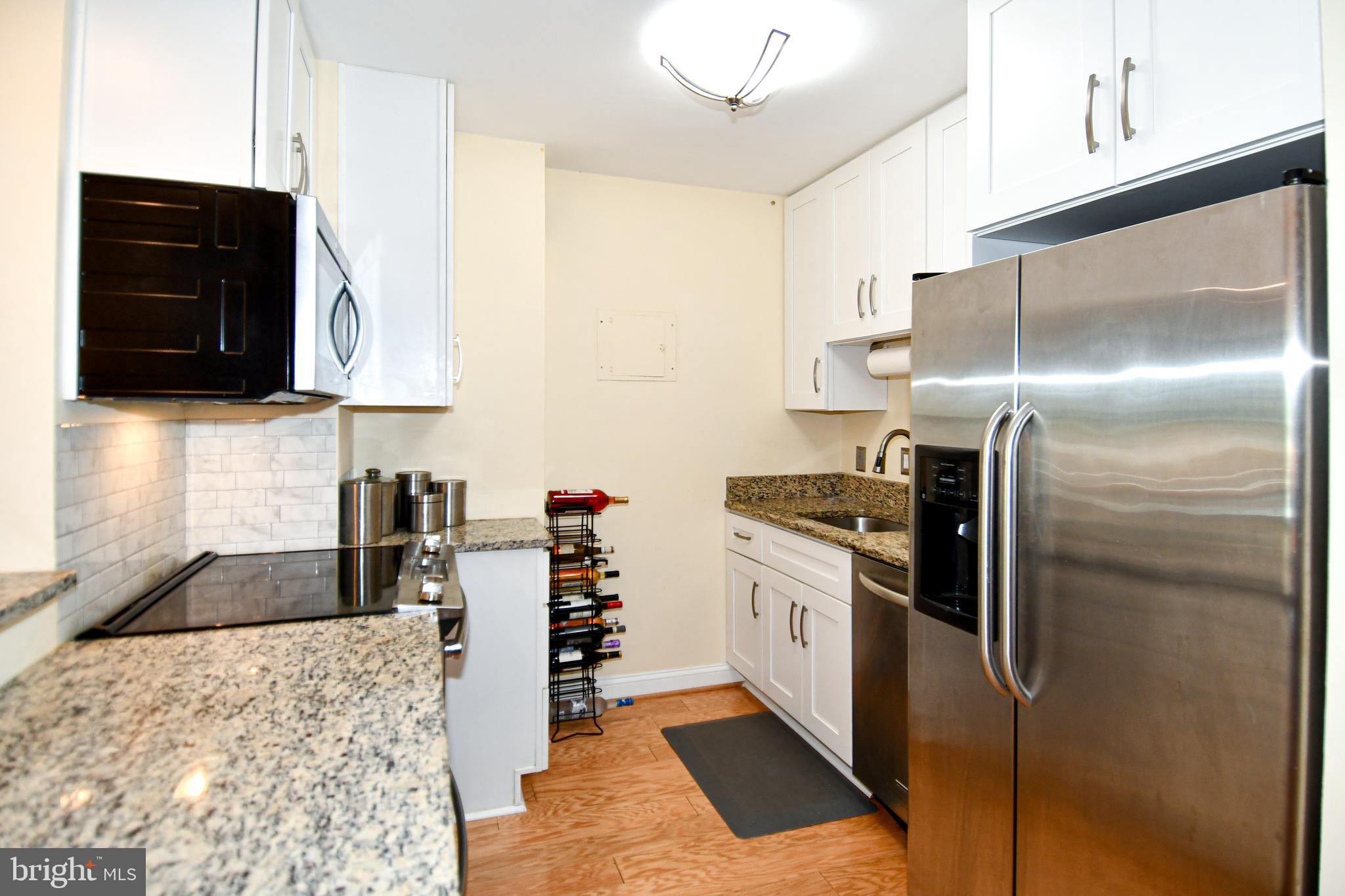 1435 4th Street Southwest, Unit B108 Washington, DC 20024 - Photo 7 of 57 a kitchen with granite countertop a refrigerator and a stove top oven