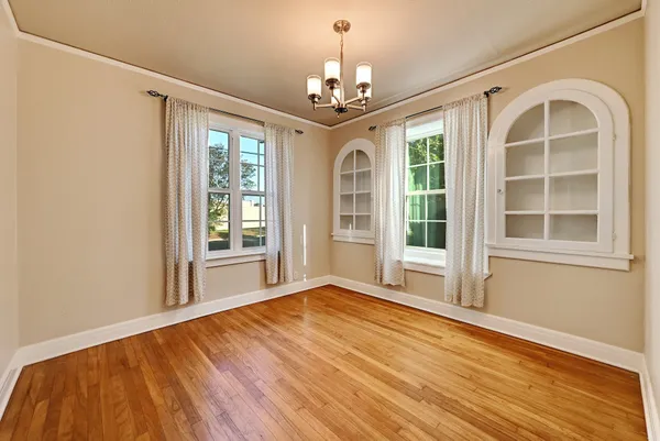 a view of an empty room with a window and wooden floor