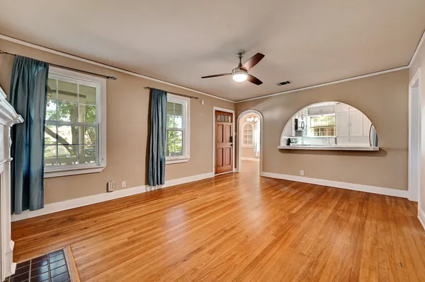 a view of empty room with wooden floor and fan