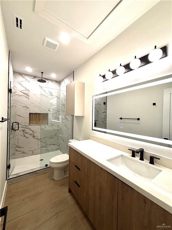 3 Estevan Street Mission, TX 78573 - Photo 7 of 22 Bathroom featuring a wood-finish vanity with an integrated sink and matte black faucet, a large back-lit mirror, and a five-light vanity fixture