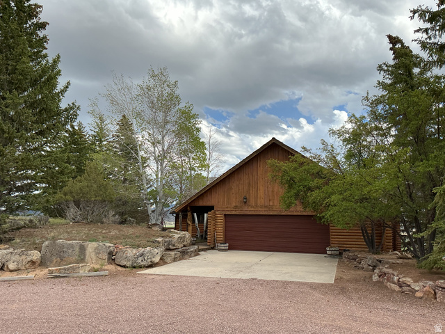 Wood-sided home featuring a concrete driveway, attached garage, and natural rock landscaping