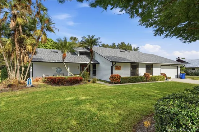 a front view of a house with a garden and trees