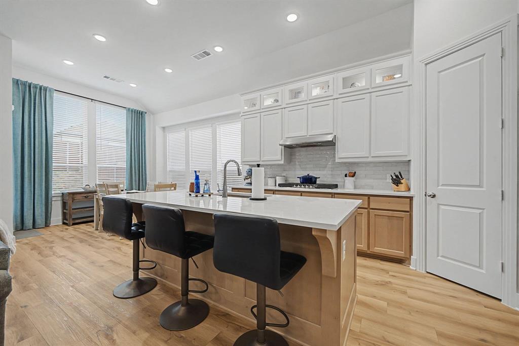 1228 Emilia Road Fate, TX 75087 - Photo 12 of 31 a kitchen with stainless steel appliances granite countertop a stove a sink a refrigerator and white cabinets with wooden floor