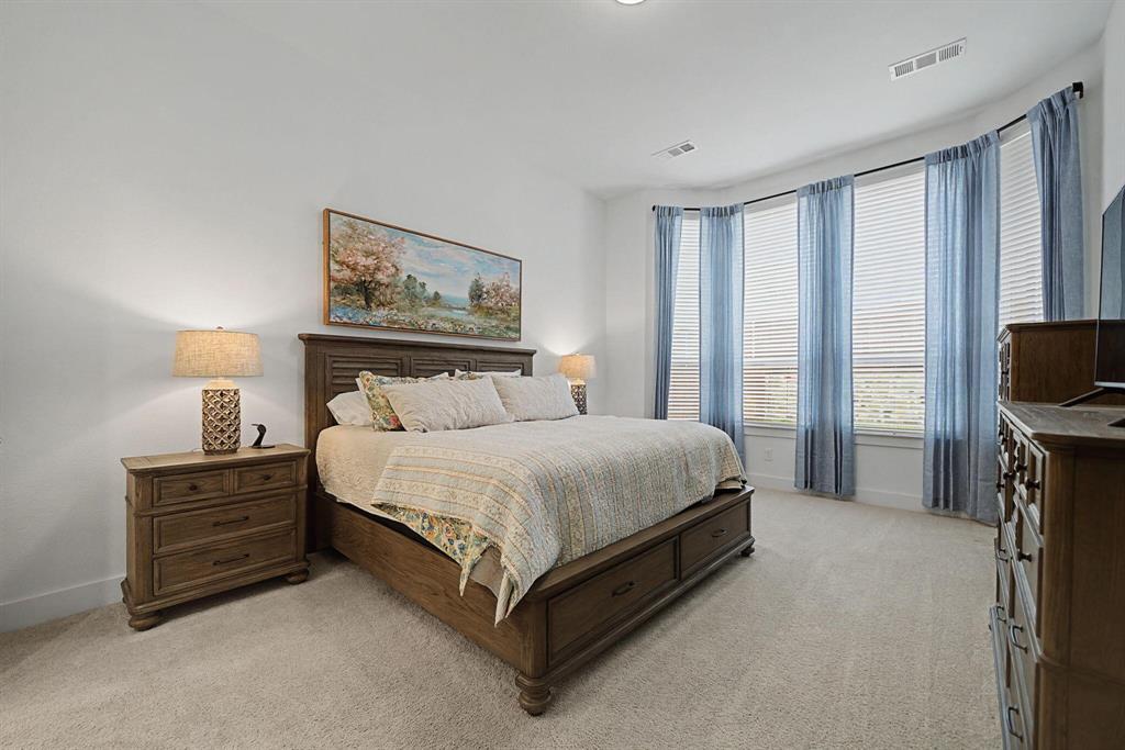 1228 Emilia Road Fate, TX 75087 - Photo 14 of 31 a spacious bedroom with a bed and a flat screen tv