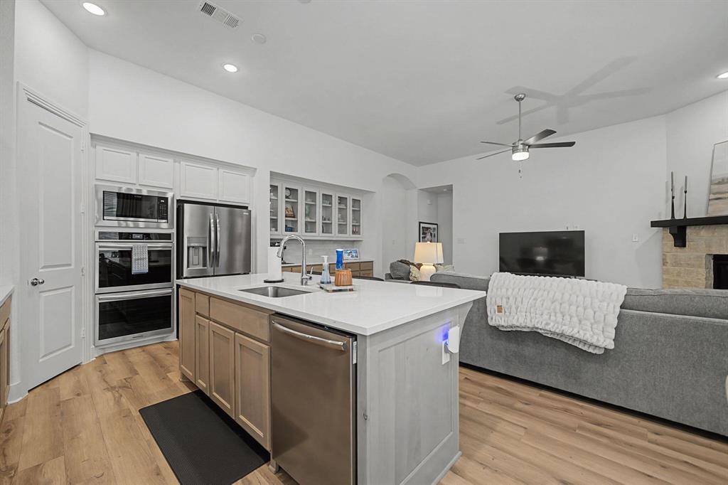 1228 Emilia Road Fate, TX 75087 - Photo 7 of 31 a large white kitchen with a stove a sink dishwasher and a refrigerator with wooden floor
