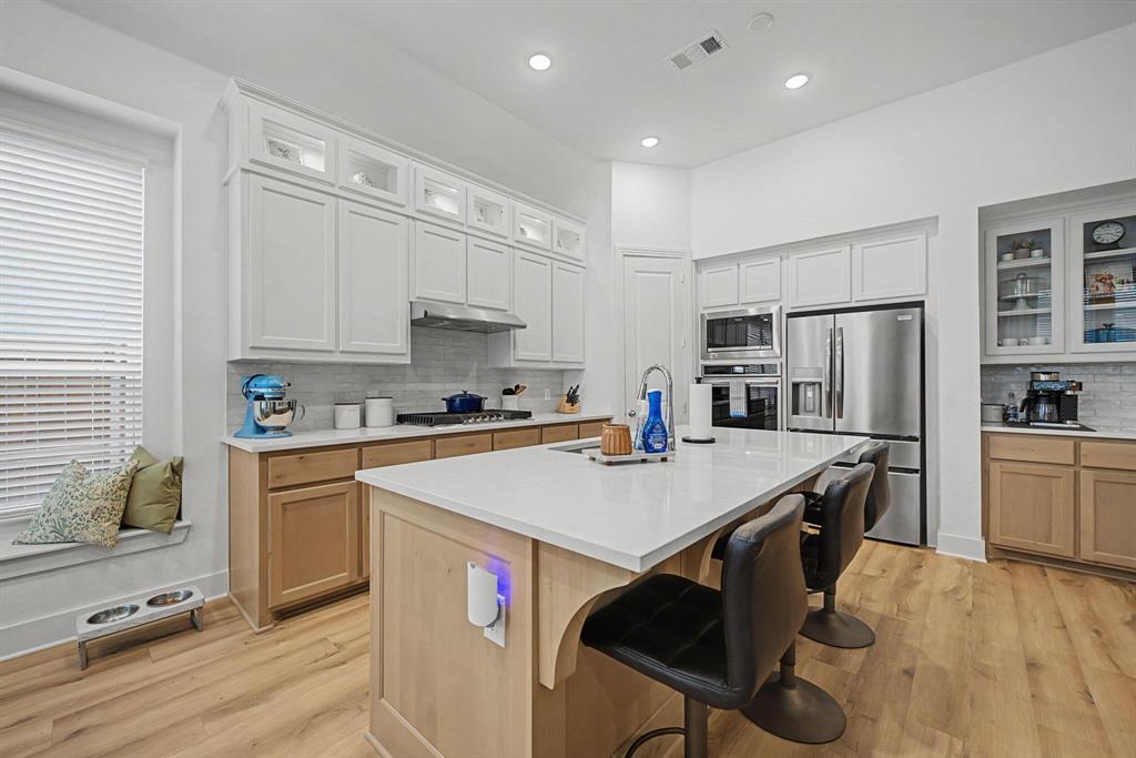 1228 Emilia Road Fate, TX 75087 - Photo 8 of 31 a kitchen with a refrigerator a stove top oven a sink dishwasher and white cabinets with wooden floor
