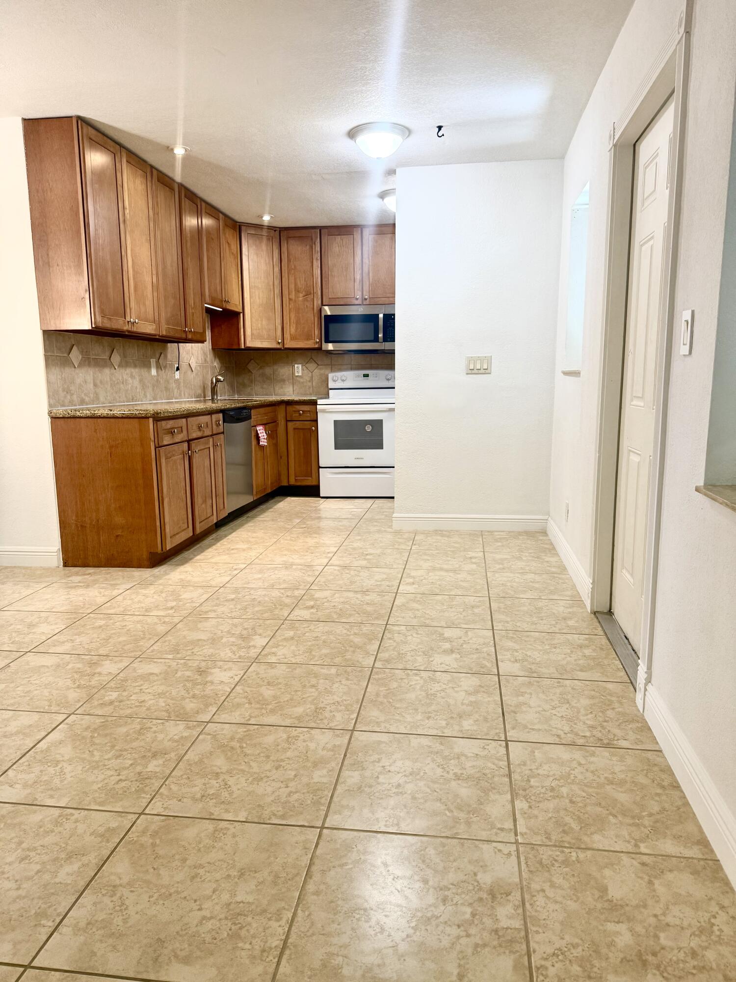 199 East McNab Road, Unit 109 Pompano Beach, FL 33060 - Photo 13 of 17 a large kitchen with granite countertop a stove a sink a microwave and a refrigerator