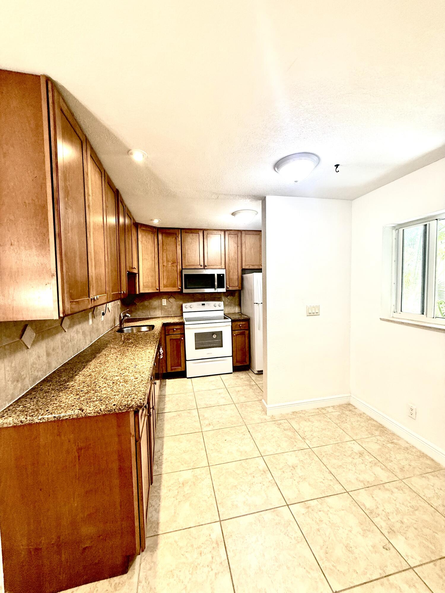 199 East McNab Road, Unit 109 Pompano Beach, FL 33060 - Photo 14 of 17 a kitchen with stainless steel appliances granite countertop a sink and cabinets