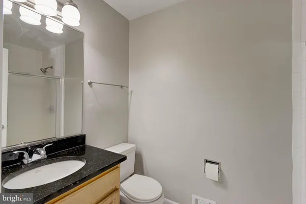 a bathroom with a granite countertop sink toilet a mirror and a shower