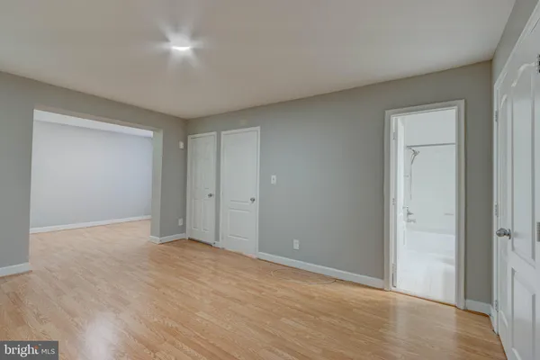 a view of an empty room with wooden floor and closet